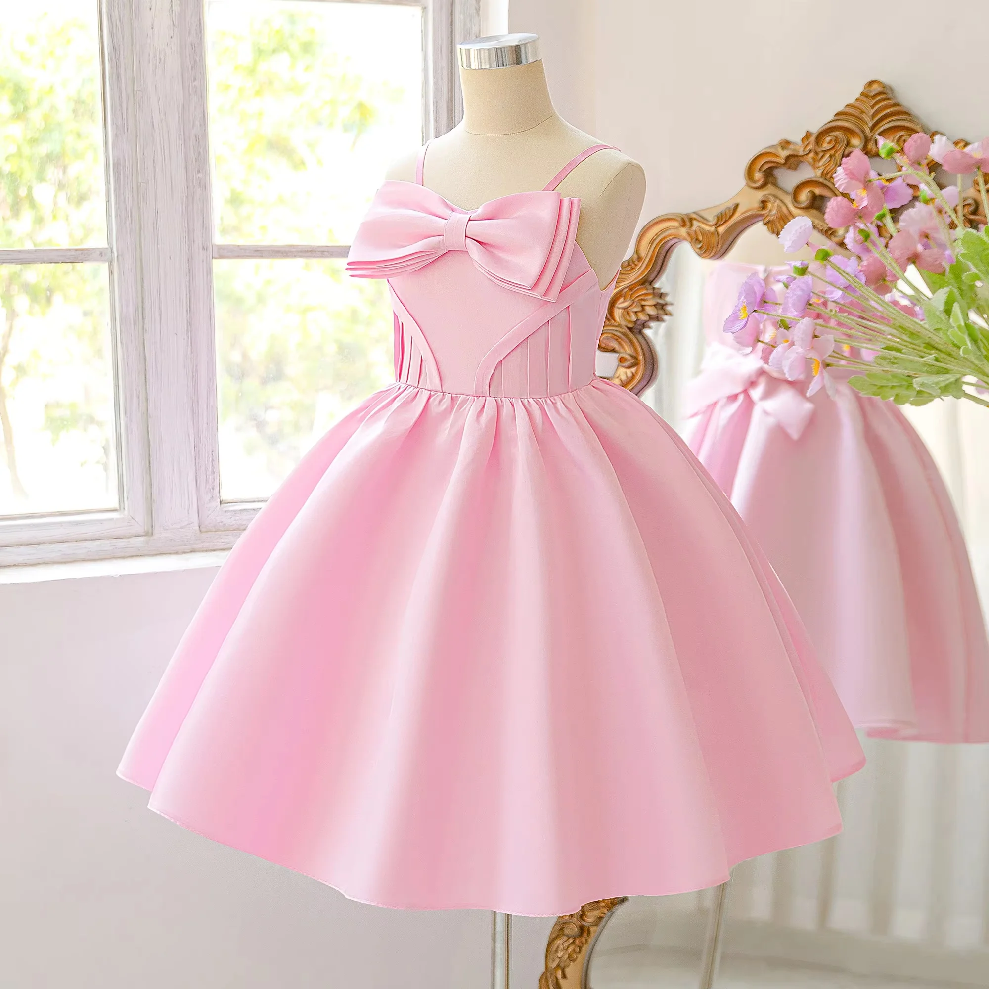 Pink kids short gown with thin spaghetti straps and bow decoration on chest. Fluffy tulle skirt looks sweet and fresh. Custom si