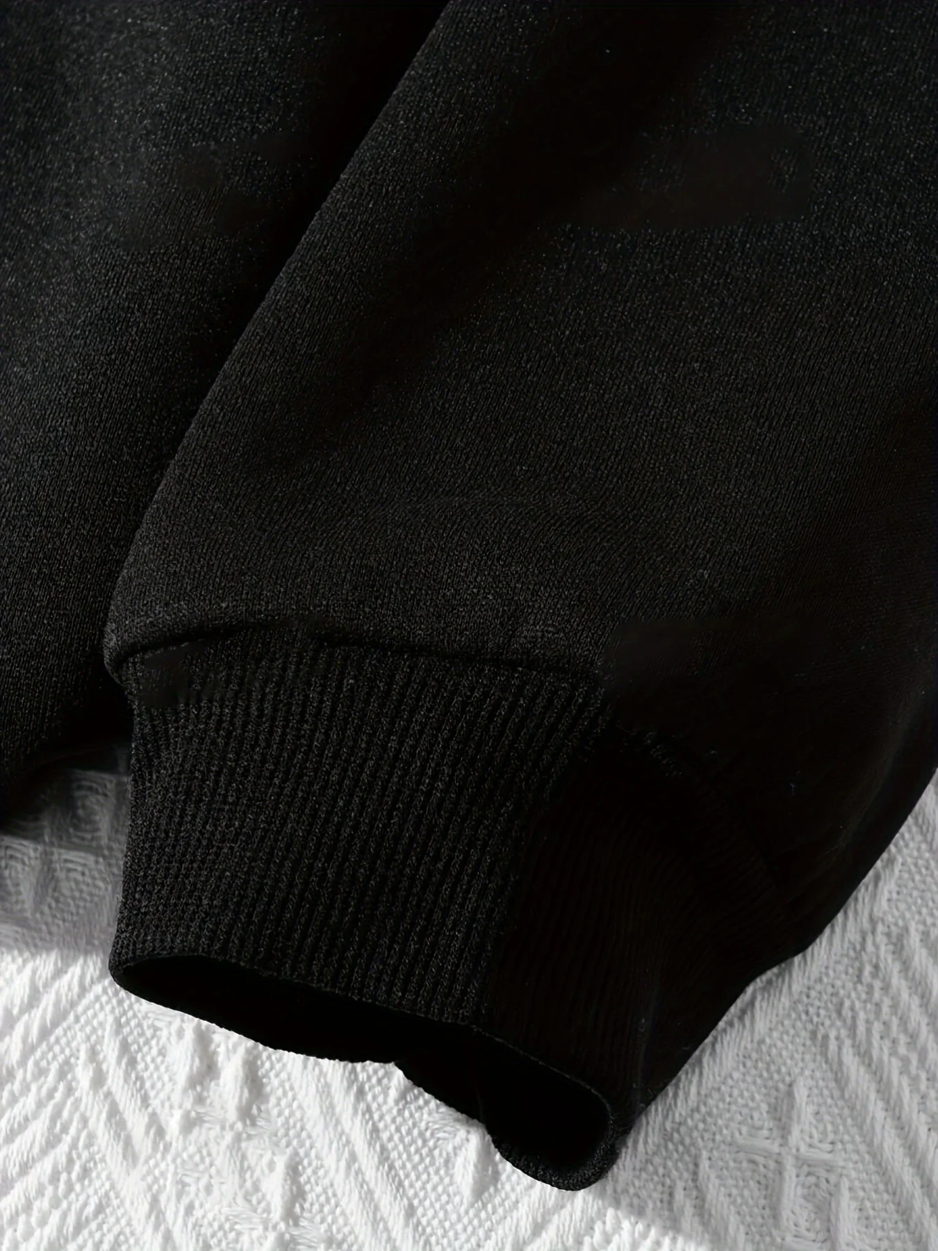 Un sweat à capuche saisonnier mondial avec une base noire imprimée avec les mots "To Teach is to Love" en fibre de polyester lavable en machine