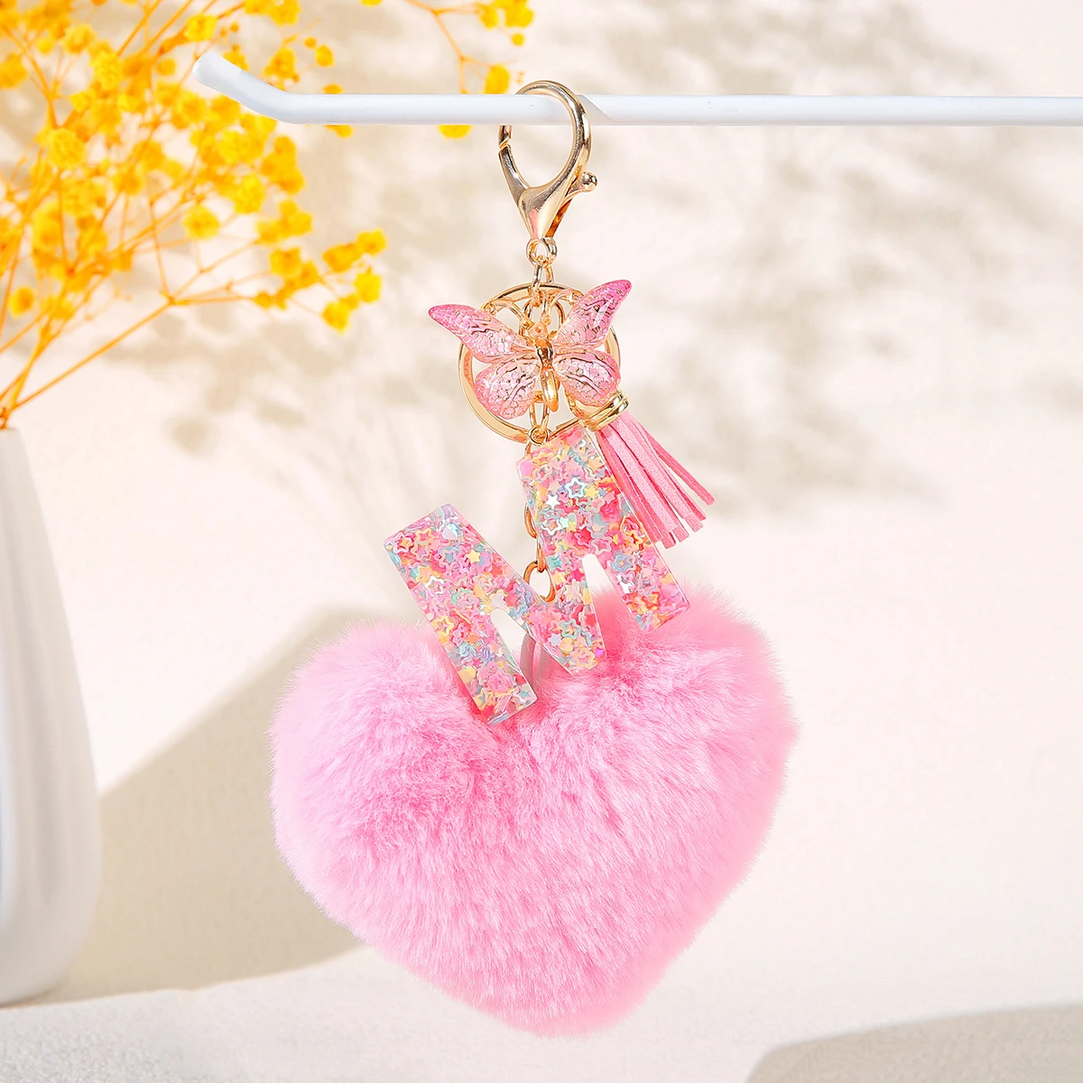 Llavero con inicial de bola de pelo de corazón rosa con flecos de mariposa, llavero de 26 letras, llavero de coche, adorno colgante para bolso de mujer