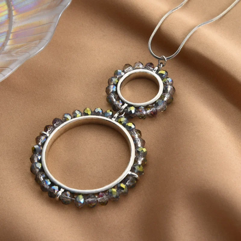 Una semplice nuova collana lunga a doppio anello, abbinata a una catena di maglioni di cristallo di diamanti nel cerchio della moda delle donne alla moda