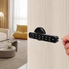 Black electronic door lock or control panel being installed or demonstrated on white door, with living room furniture visible in background.