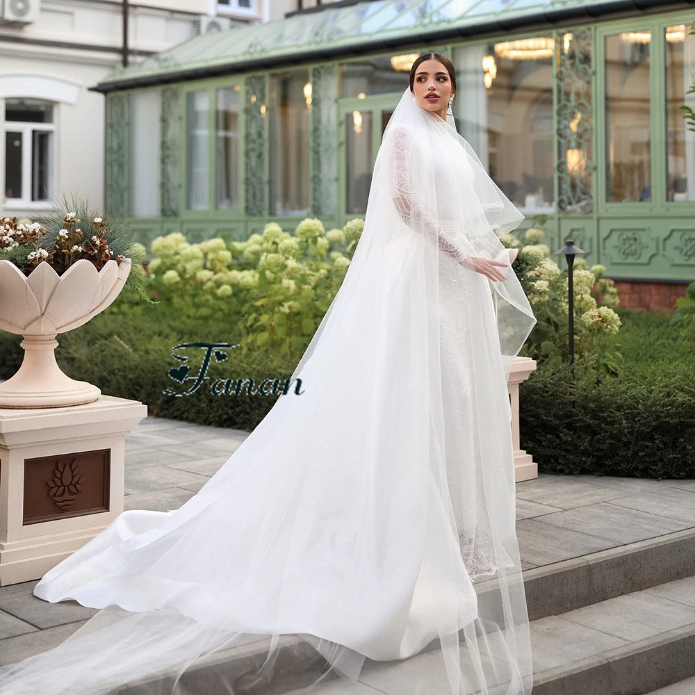 Suknia ślubna z białej koronki z dekoltem w kształcie litery O, z iluzorycznymi, długimi rękawami, trenem Watteau, długości do podłogi, o kroju syreny.