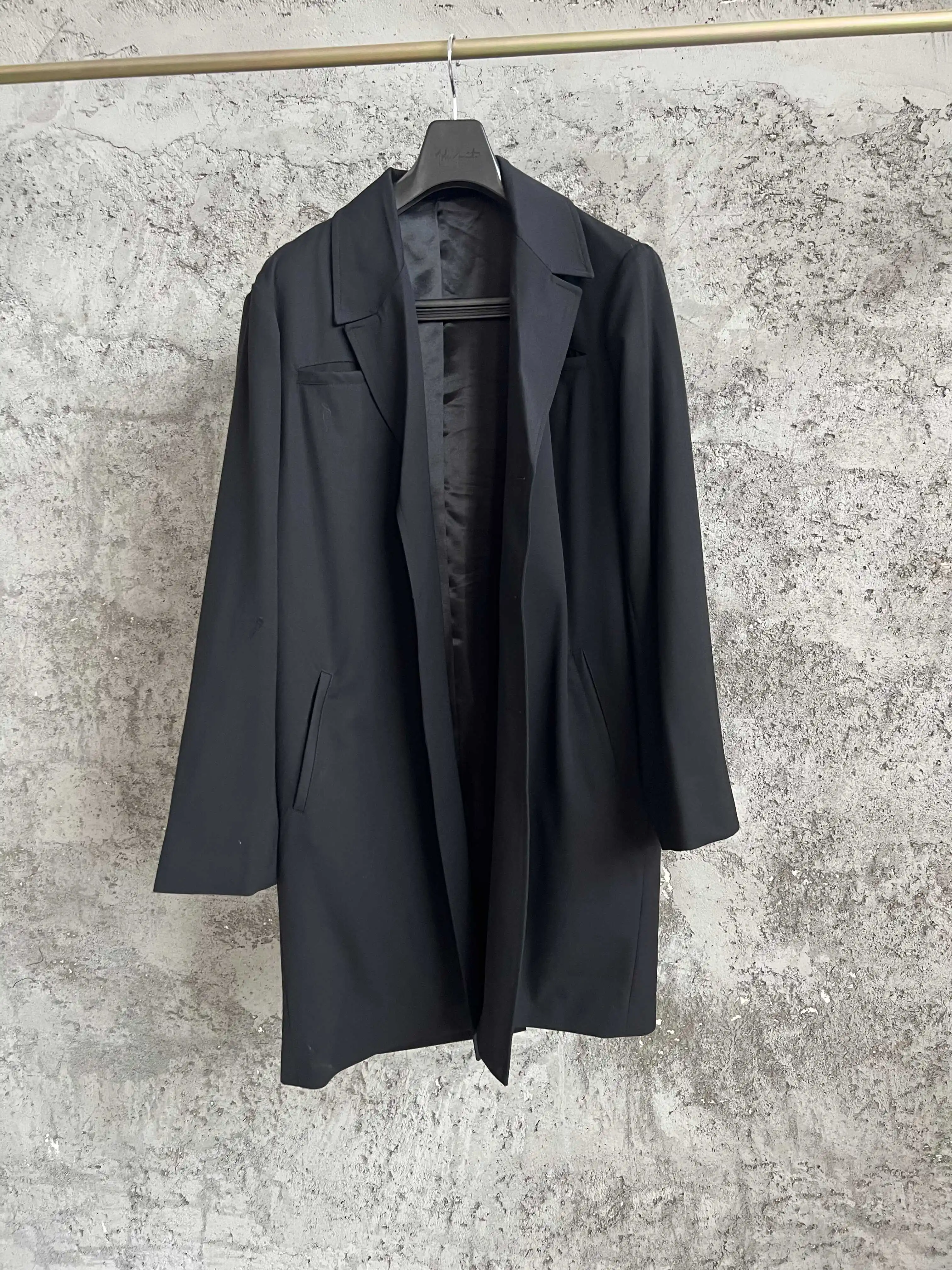 

A black suit with a slanted lapel, single-breasted design and an irregular hem