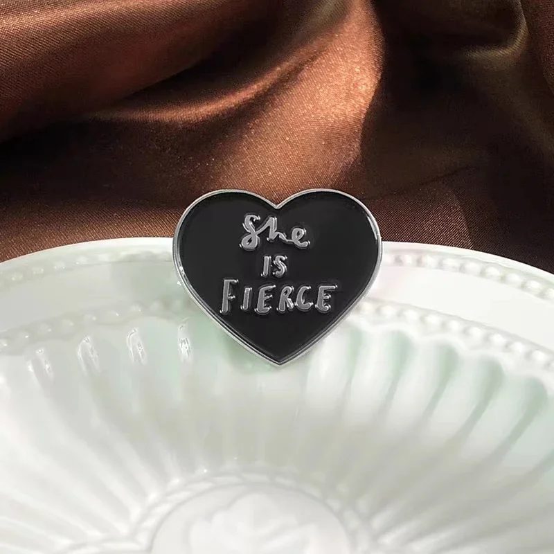 Pin de esmalte de corazón negro con cita en inglés, She is fierce broche de, accesorio de solapa para bolso, insignia, regalo para Amiga, joyería al por mayor