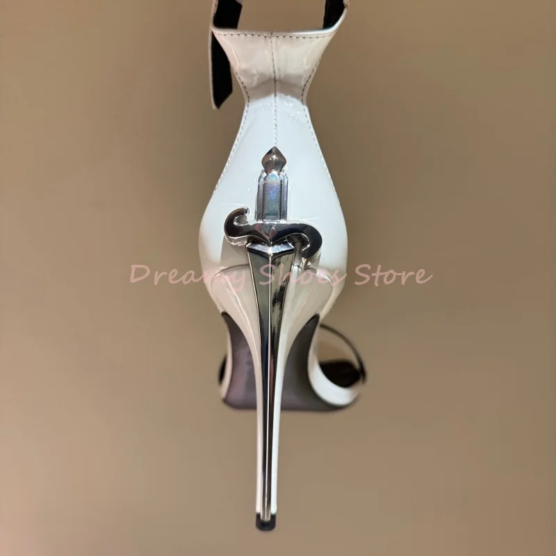 Sandalias de tacón de aguja con una correa en forma de espada blanca para mujer, zapatos de fiesta de charol a la moda con punta abierta y decoración de Metal plateado