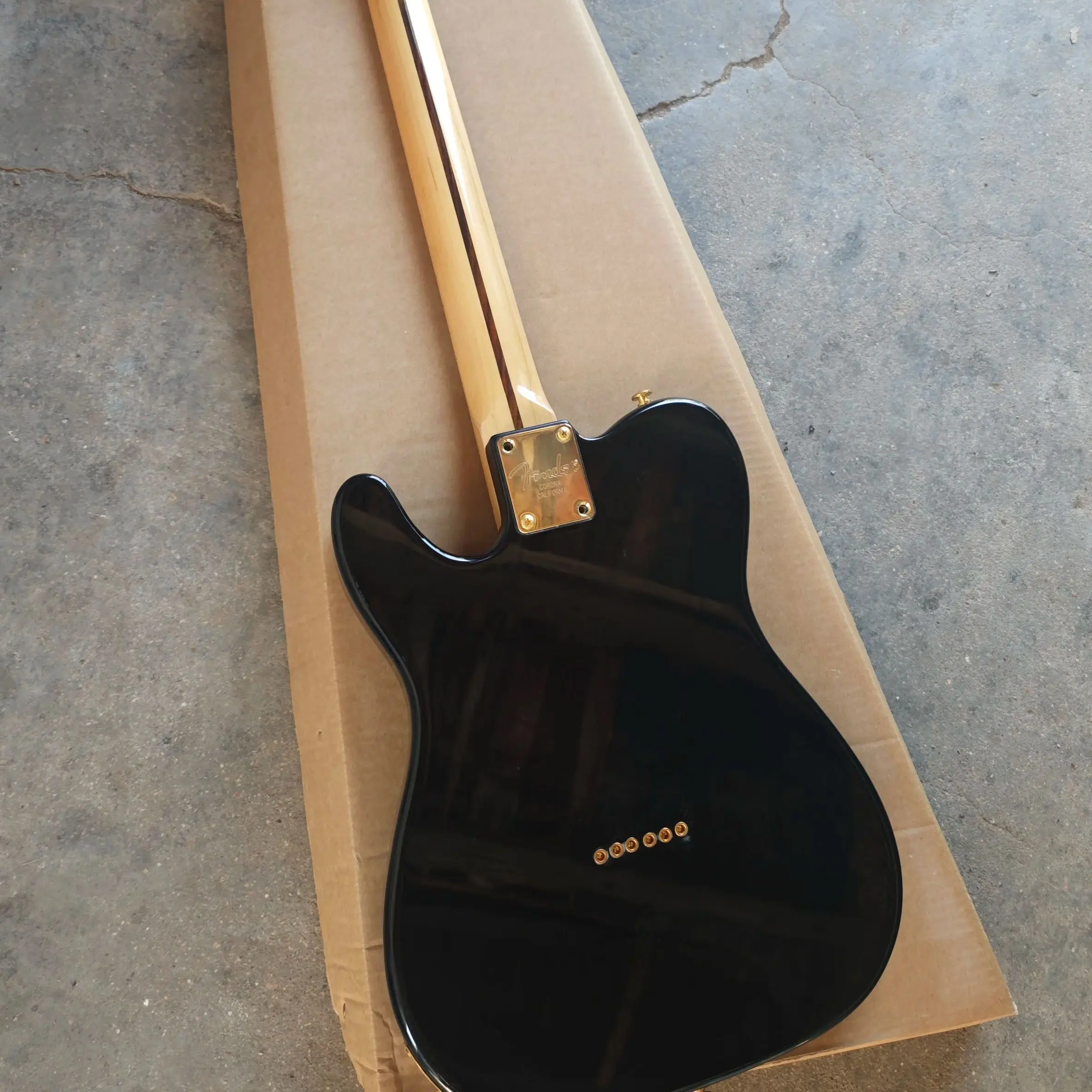 Black six-string electric guitar, gold printed basswood body, maple neck and maple fingerboard with gold hardware.