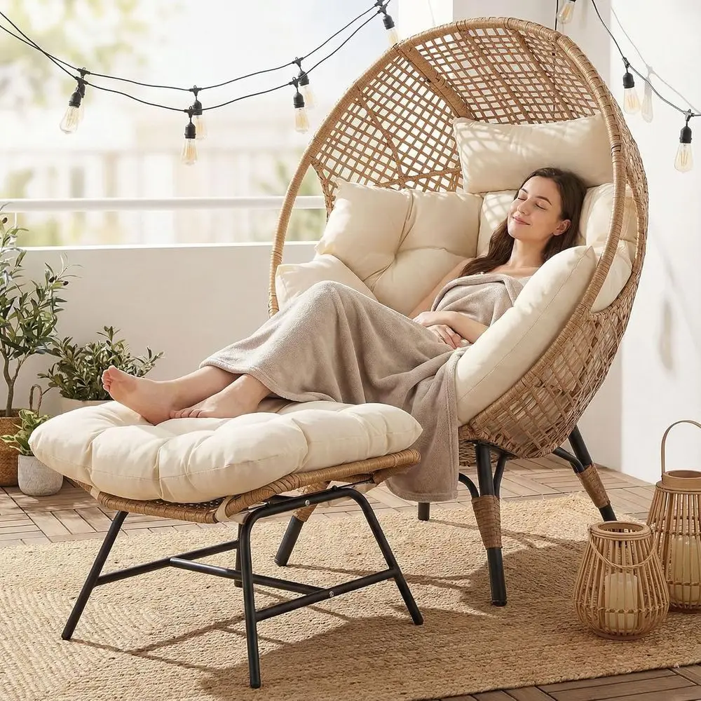 Zenith Oversized Woven Rattan Nest Chair with Ottoman in a cozy outdoor evening setting