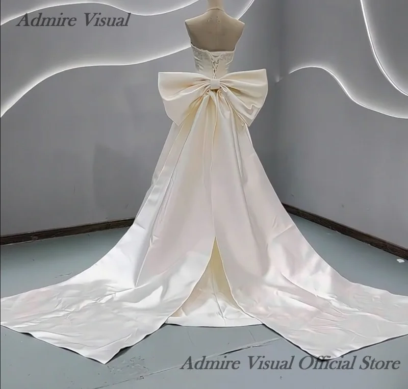분리 가능한 큰 리본이 달린 A라인 새틴 민소매 비주얼 웨딩드레스를 감상하세요. 맞춤 제작 가능한 신부 가운