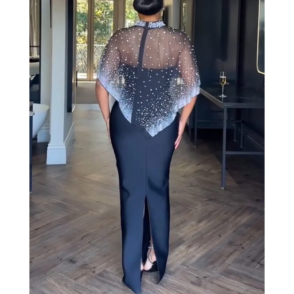 Dwuczęściowy strój: dopasowana sukienka maxi bez ramiączek z rozcięciem z tyłu na zamek i przezroczysta peleryna z siateczki z wysokim dekoltem, zdobiona cyrkoniami i perłami, zapinana na zamek z tyłu.