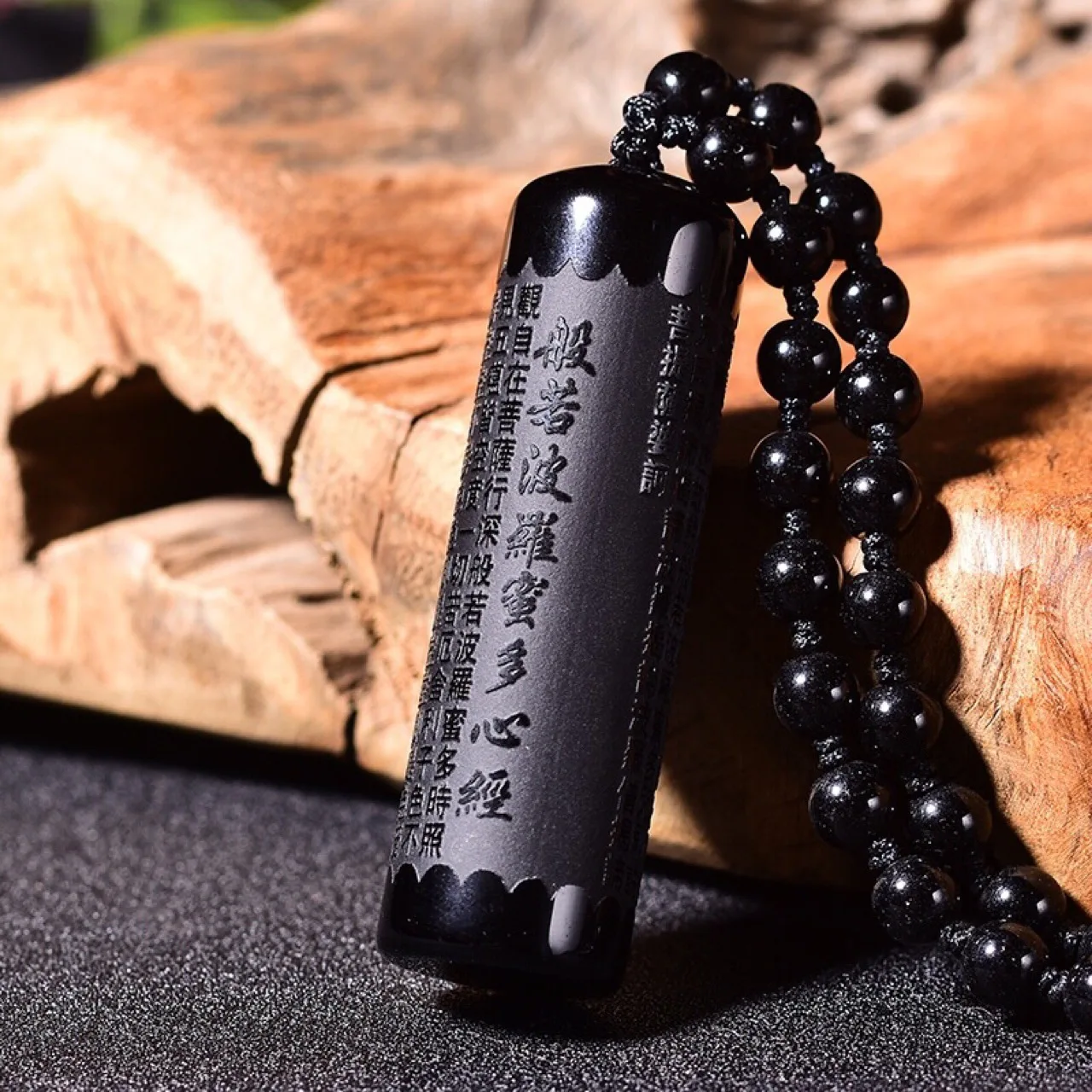 Natural obsidian prajna paramita pendant on a pillar