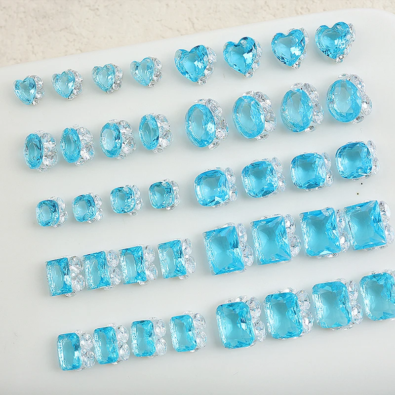 เครื่องประดับเล็บสีฟ้าน้ำแข็งระดับพรีเมียม 20 ชิ้นพร้อมคิวบิกเซอร์โคเนียที่วางอยู่ด้วยมือ โดดเด่นด้วยรูปทรงเรขาคณิตแบบซ้อนและรูปหัวใจ