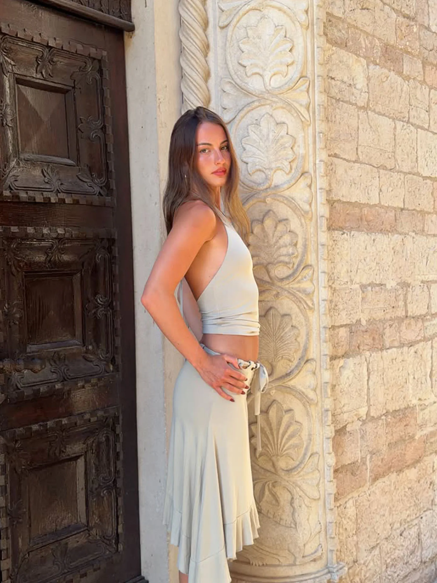 With Jen beige halter-neck backless top and black skirt with waist cut-outs and an asymmetric hem.
