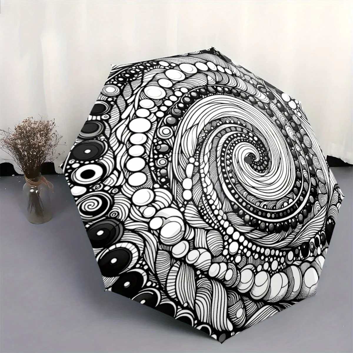 

Автоматический складной зонт. Зонт имеет черно-белый спиральный узор с круговыми элементами. Портативный складной