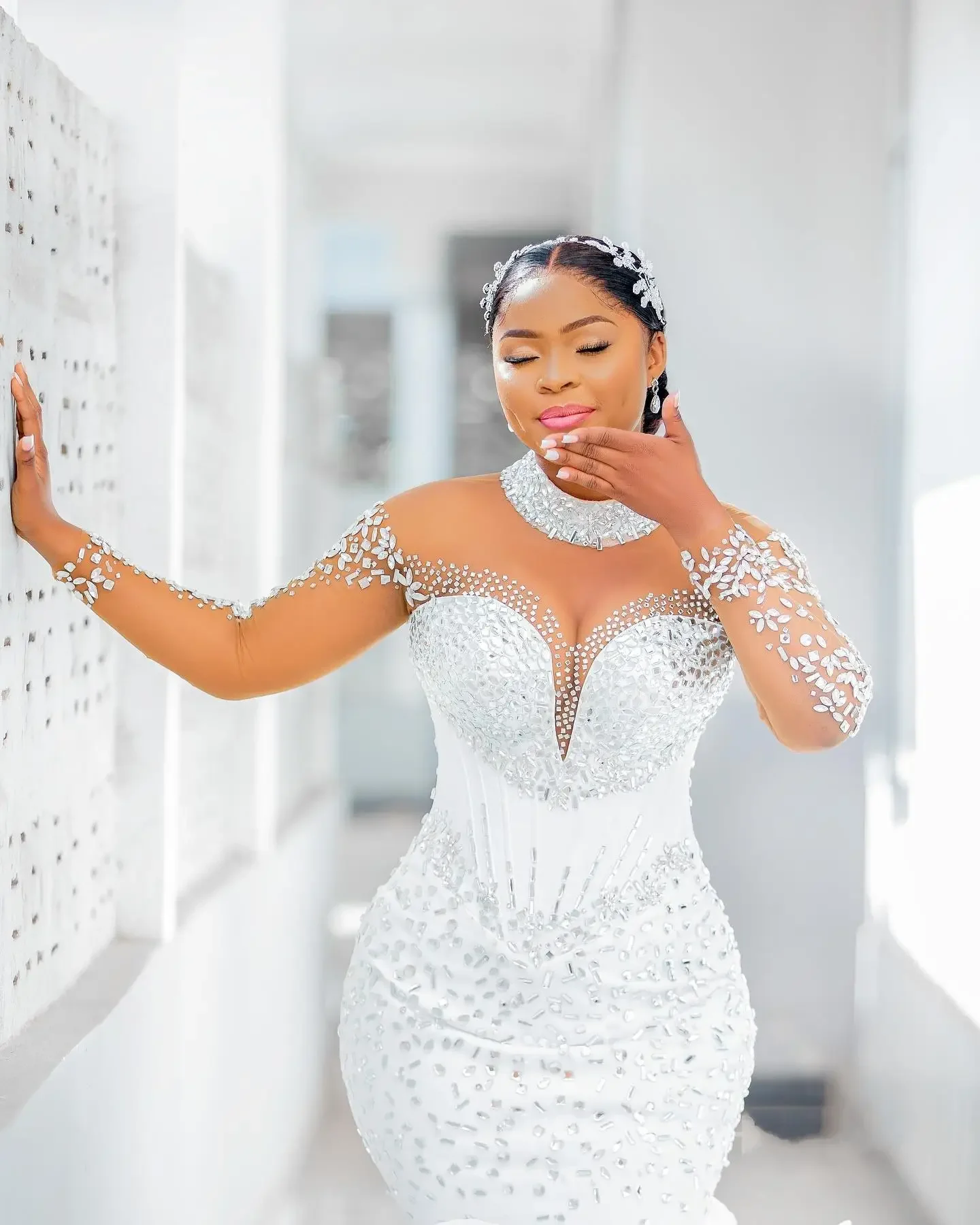 Suknia ślubna syrena z wysokim dekoltem, zdobiona błyszczącymi kryształkami i cyrkoniami, z długimi rękawami i kaskadowymi falbanami, szyta na miarę.