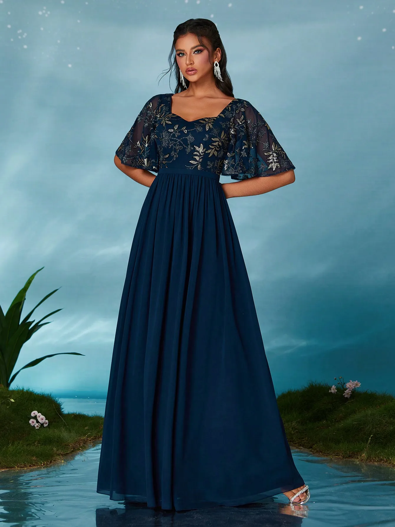 Ein hochwertiges Abendkleid mit aufgestickten Pailletten, quadratischem Ausschnitt, mittleren Ärmeln und großem Saum