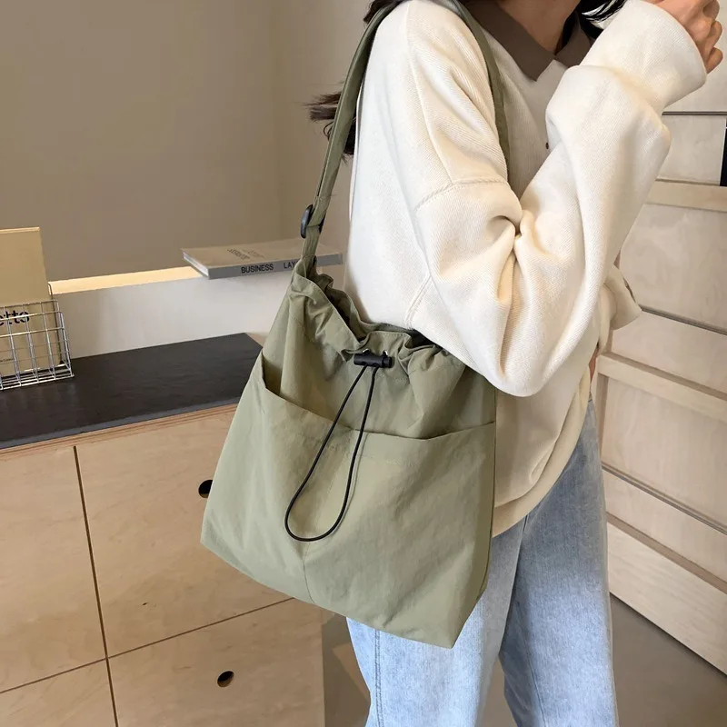 bolsa-de-ombro-de-lona-com-cordao-e-alca-ajustavel-design-moderno-com-pingente-bolsa-casual-e-leve-ideal-para-o-dia-a-dia-e-para-usar-transversalmente