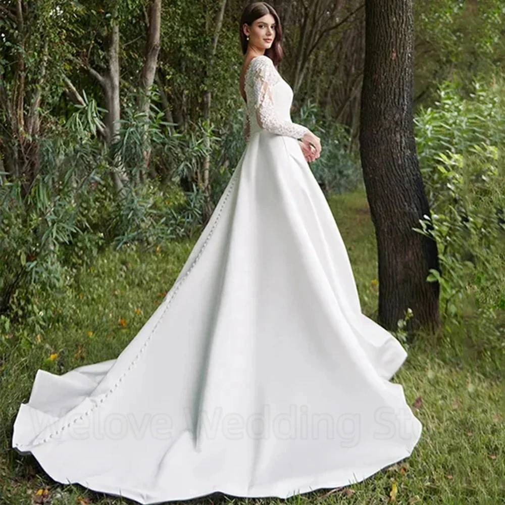 فستان زفاف أنيق بأكمام طويلة من الدانتيل والساتان ورقبة على شكل حرف V بطول الأرض مع أزرار وجيب فساتين زفاف بحزام خلفي مفتوح