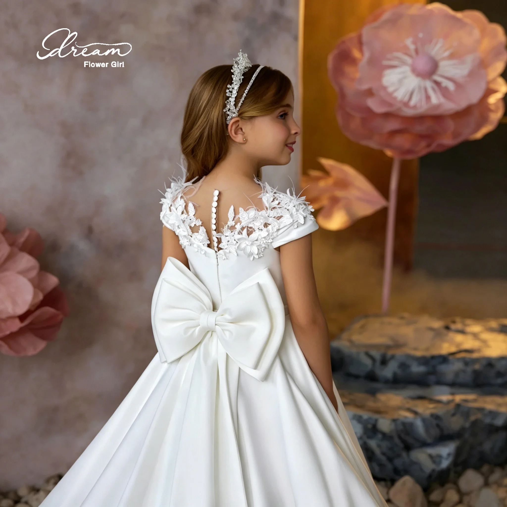 Elegant flower girl's white satin A-line dress, floor-length evening gown, featuring embroidered neckline and bow details.