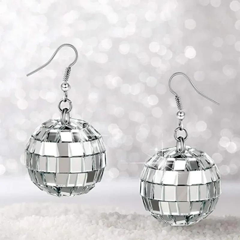 

Each earring features a faceted mirror-ball pendant, designed to reflect light like a classic disco ball. Set on simple silver-toned hooks, they create a retro