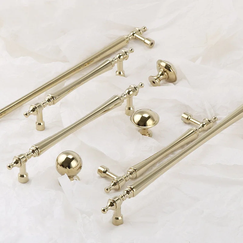 Gold brass pulls and round knobs arranged on a marble surface
