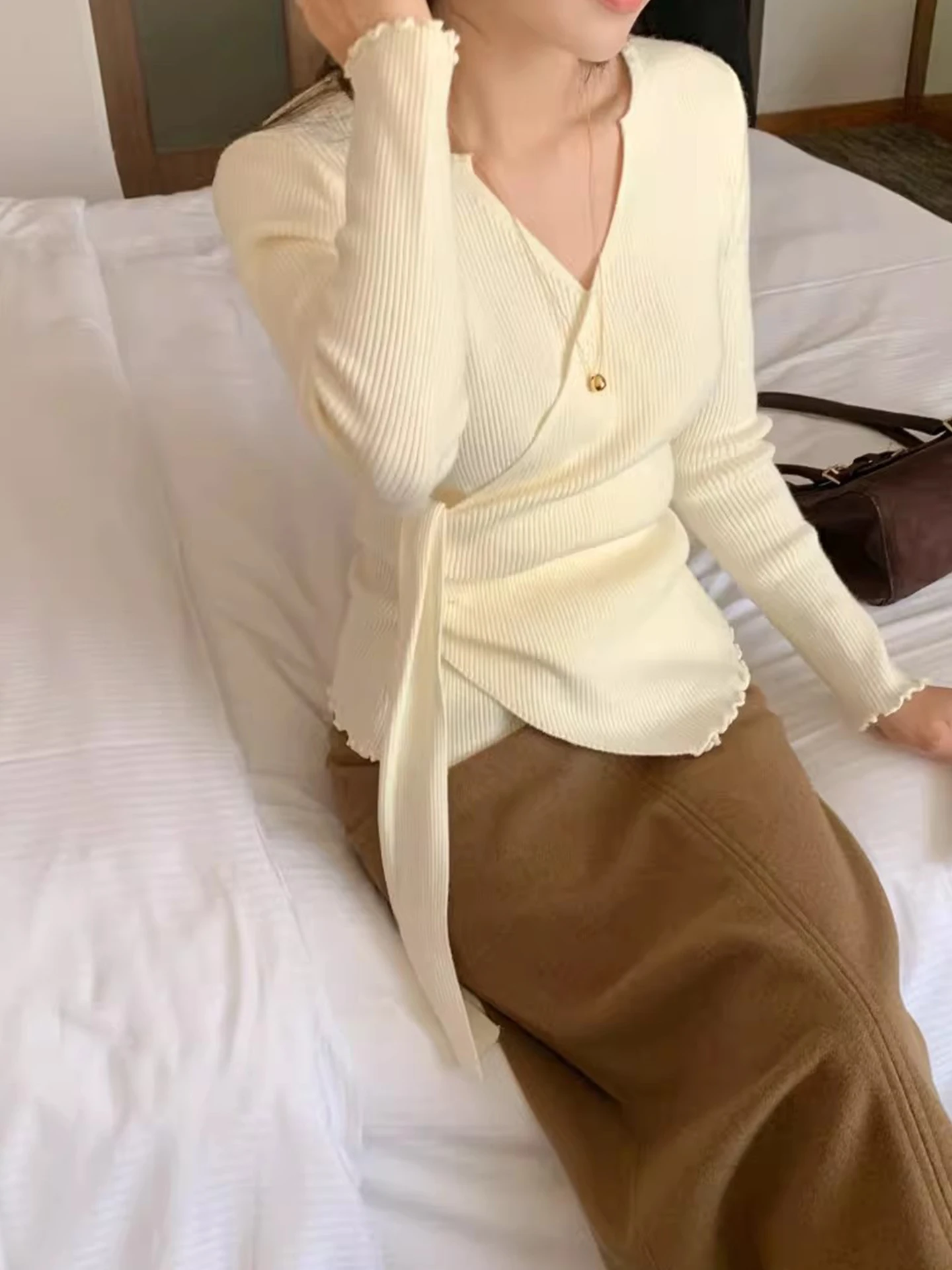 เสื้อสเวตเตอร์ถักคอวีไขว้สำหรับผู้หญิง ทรงเข้ารูป ใส่เป็นเสื้อตัวในได้ เหมาะสำหรับฤดูใบไม้ร่วงและฤดูหนาว เนื้อผ้านุ่มสบาย ดีไซน์ทันสมัย พร้อมดีเทลผูกโบว์ที่คอเสื้อ