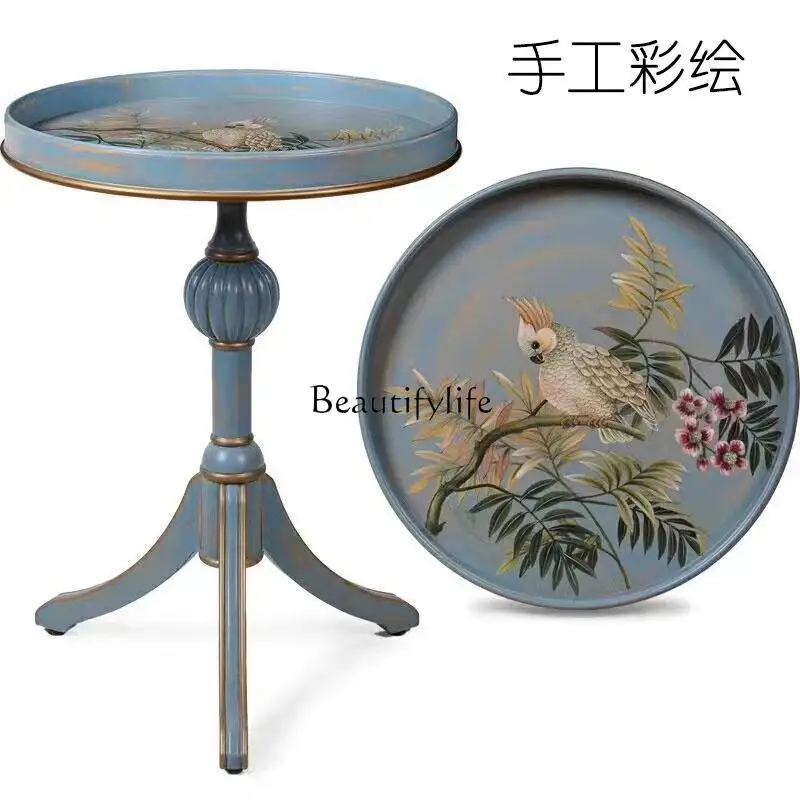 **โต๊ะกลมเล็กทาสีมือสไตล์อเมริกันในชนบท โซฟาไม่กี่มุมในห้องนั่งเล่น และโต๊ะกลมไม่กี่ตัว