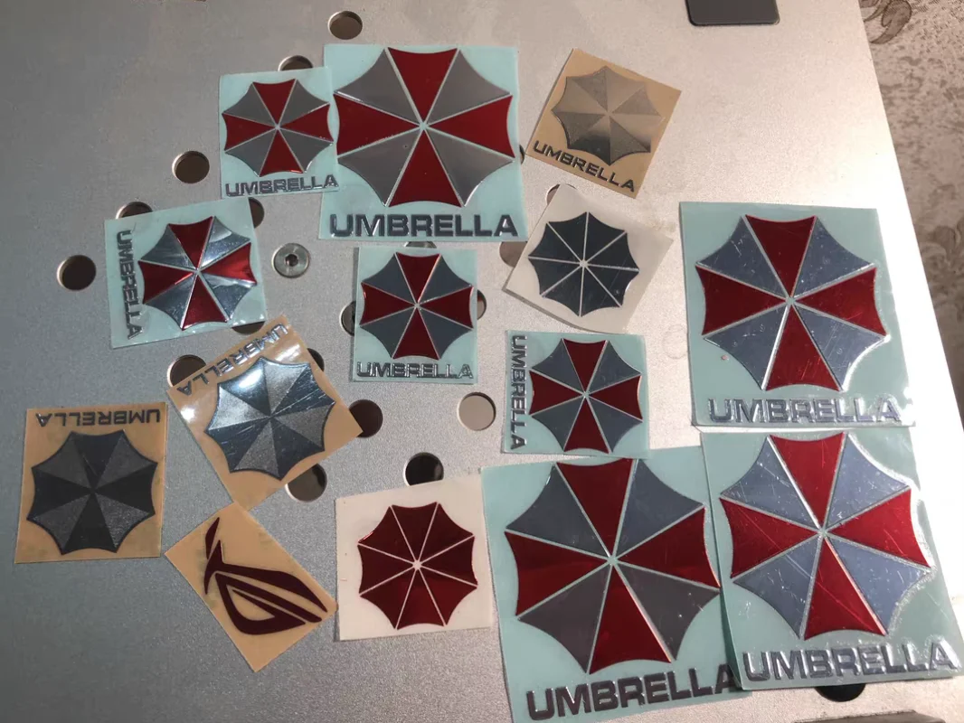 O adesivo de metal The Resident Evil Umbrella Phone é adequado para laptops, carros, pranchas de trabalho, bancos de energia, tablets e decorações