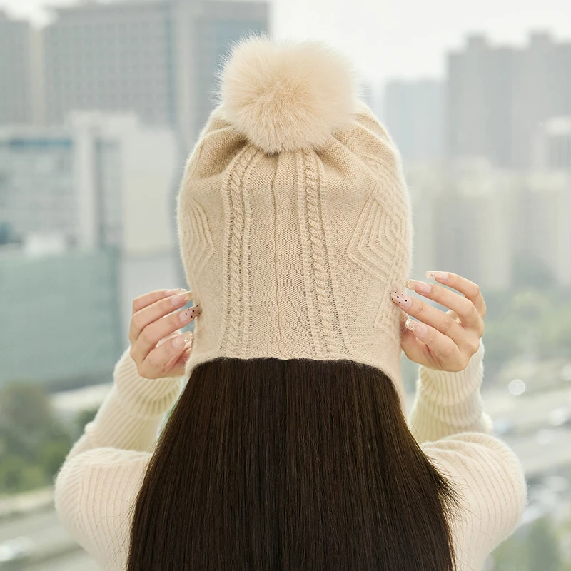 قبعة كرة شعر عصرية للسيدات شتوية سميكة 100% من الكشمير الخالص محبوكة بلون سادة قبعة حماية للأذن دافئة ومقاومة للرياح