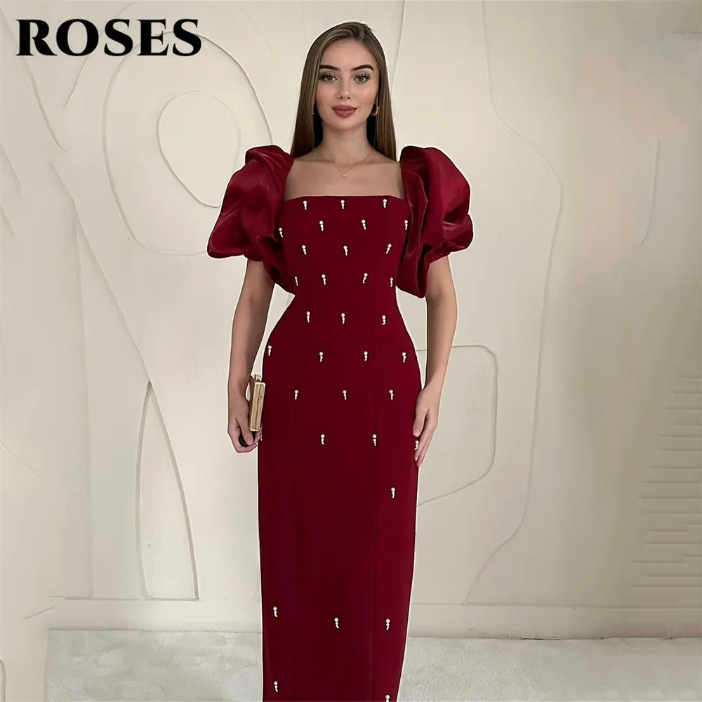 فساتين حفلة موسيقية أنيقة باللون العنابي من ROSES فساتين سهرة بخط عنق مربع وأكمام منتفخة منظمة وتفاصيل متألقة حسب الطلب