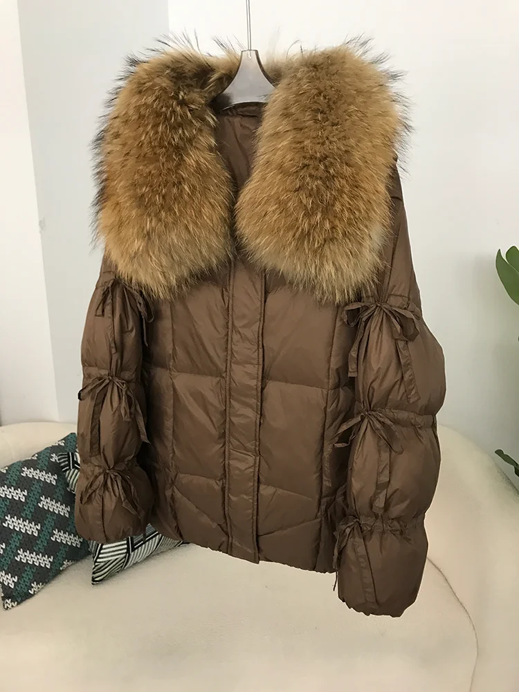 2025 الشتاء النساء بطة أسفل سترة معطف سوبر كبير ريال الراكون الفراء طوق مع ربطة القوس فيونكة كم موضة ملابس خارجية فاخرة