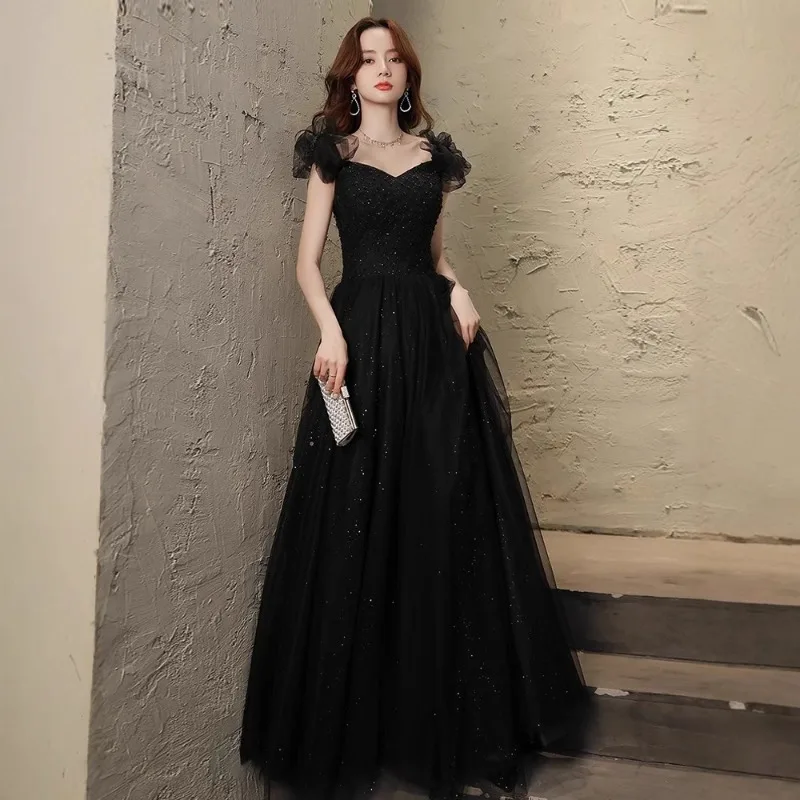 Jesienna, czarna, cekinowa suknia wieczorowa na bankiet, emanująca luksusowym i eleganckim charakterem, dopasowana i wyszczuplająca sukienka na ramiączkach.