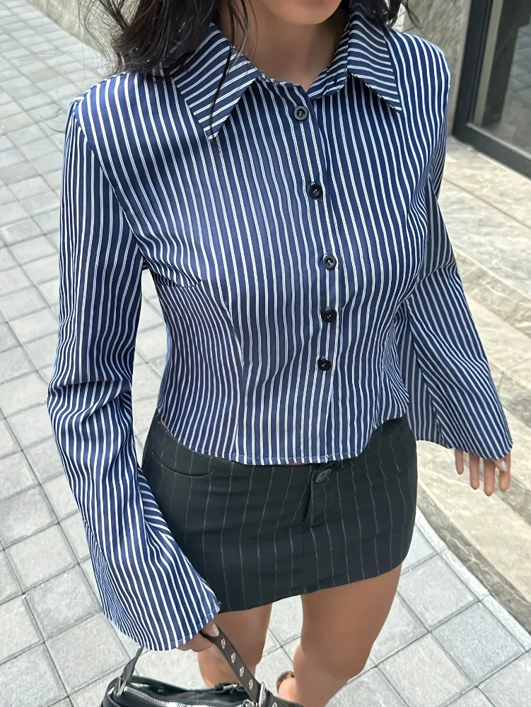 بلوزة نسائية بياقة قميص وأكمام منتفخة قصيرة بخطوط عمودية زرقاء داكنة، تصميم بسيط بأكمام واسعة قليلاً وخصر ضيق