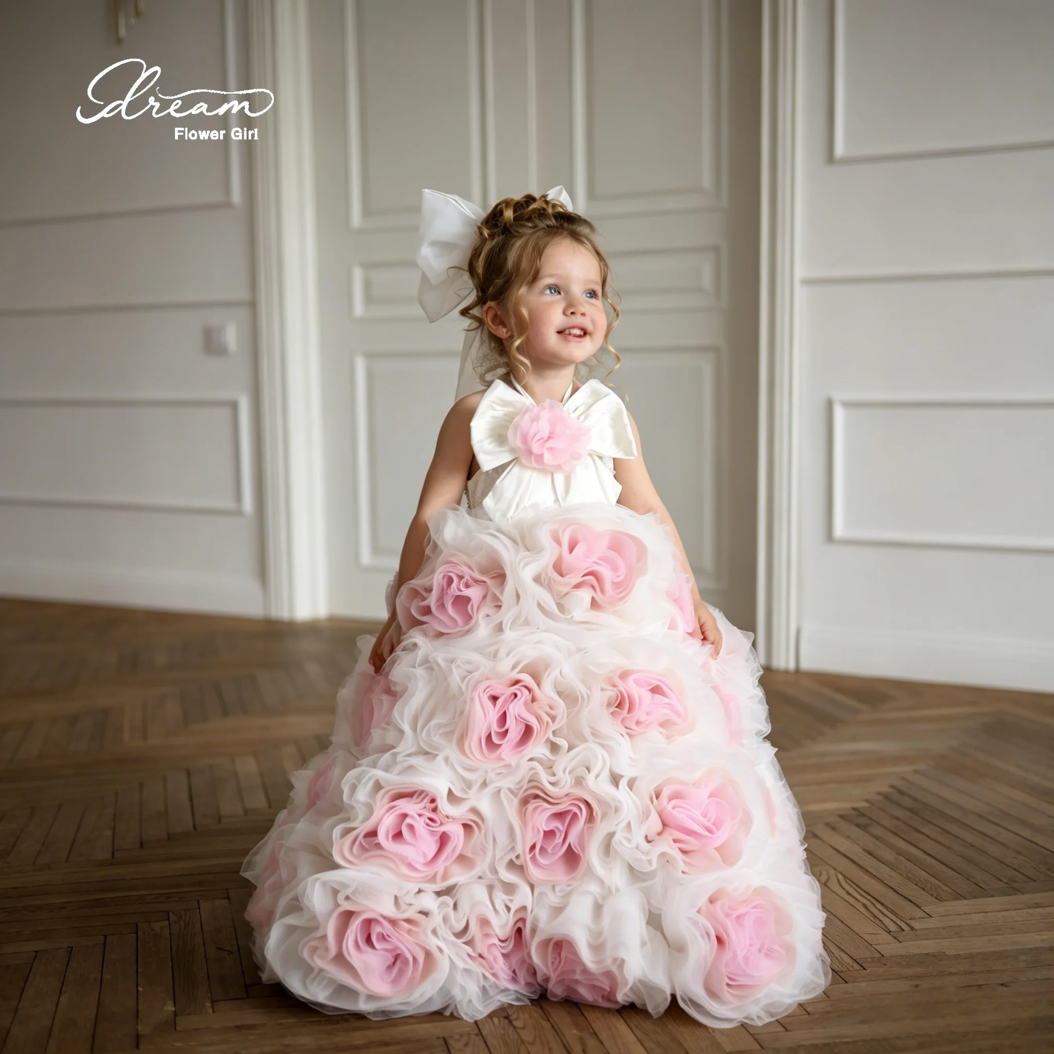 Adorable flower girl's white strapless floor-length evening dress with a fluffy skirt and pink floral decorations.