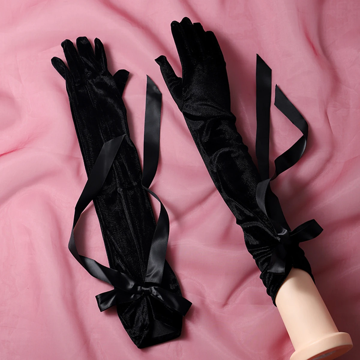 A pair of black gloves with ribbon embellishments in a finger style and elbow length, suitable as accessories for bride weddings