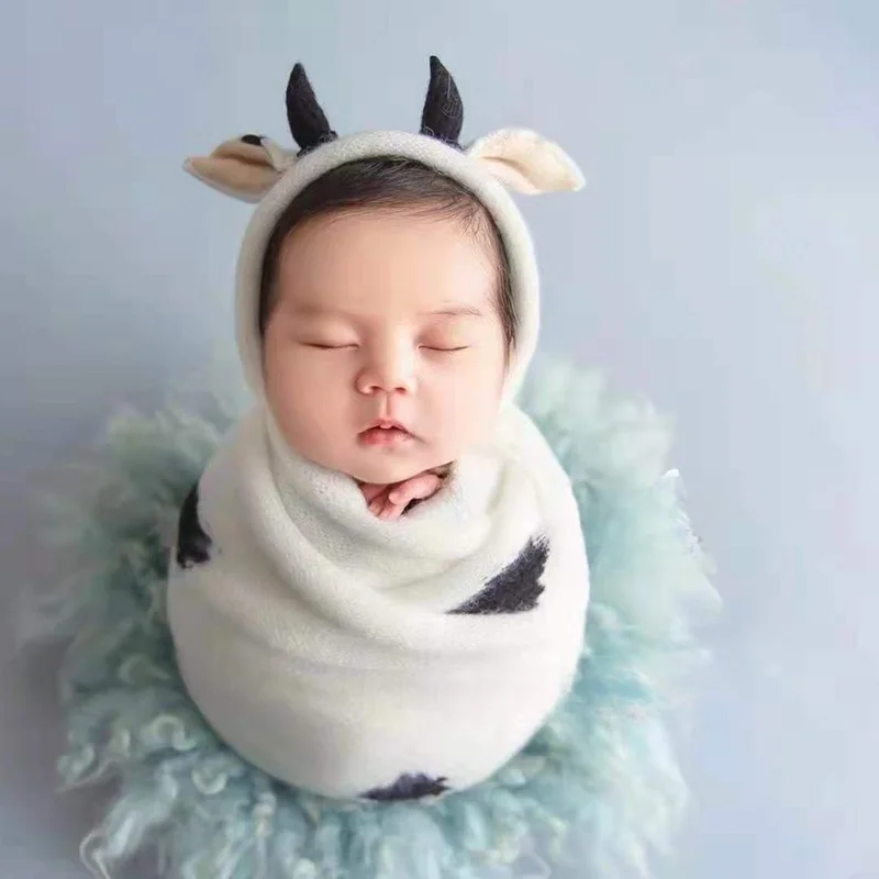 Newborn Baby with A Full Moon for 100 Days Takes Pictures of A Cow-shaped Hat Wrapped In A Cloth Towel.