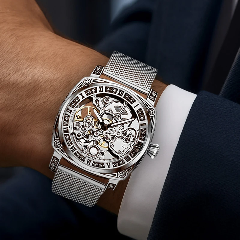 ساعة ميكانيكية أوتوماتيكية بالكامل بحزام شبكي فضي وأنيق على طراز المؤشر وأرقام رومانية للرجال.