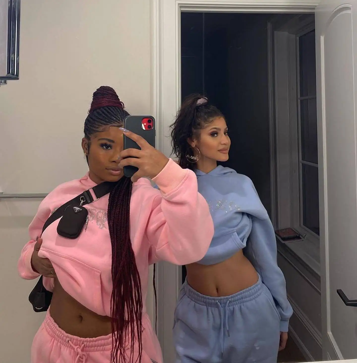 Woman wearing a matching hooded sweatshirt and running pants sportswear set in casual street style pink and blue