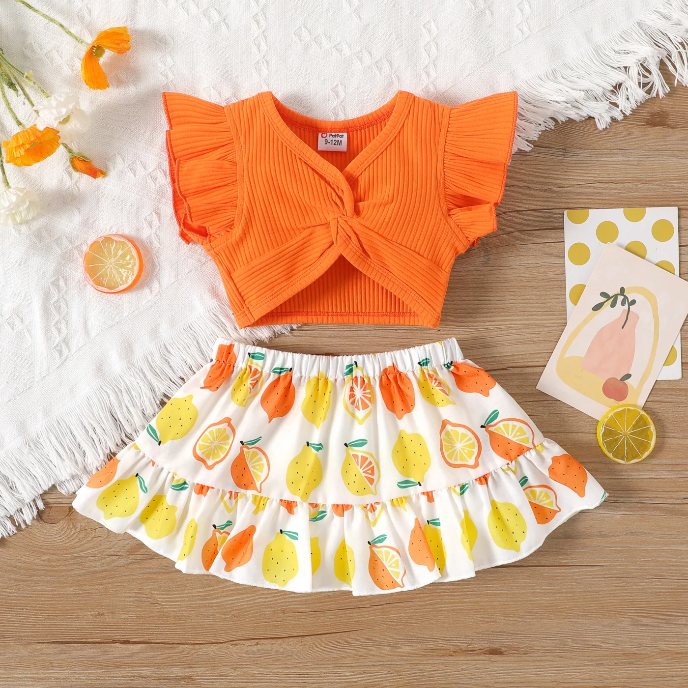 

PatPat 2pcs Baby Girl Solid Cotton Ribbed Ruffle-sleeve Twist Knot Crop Top and Allover Fruit Print Skirt Set