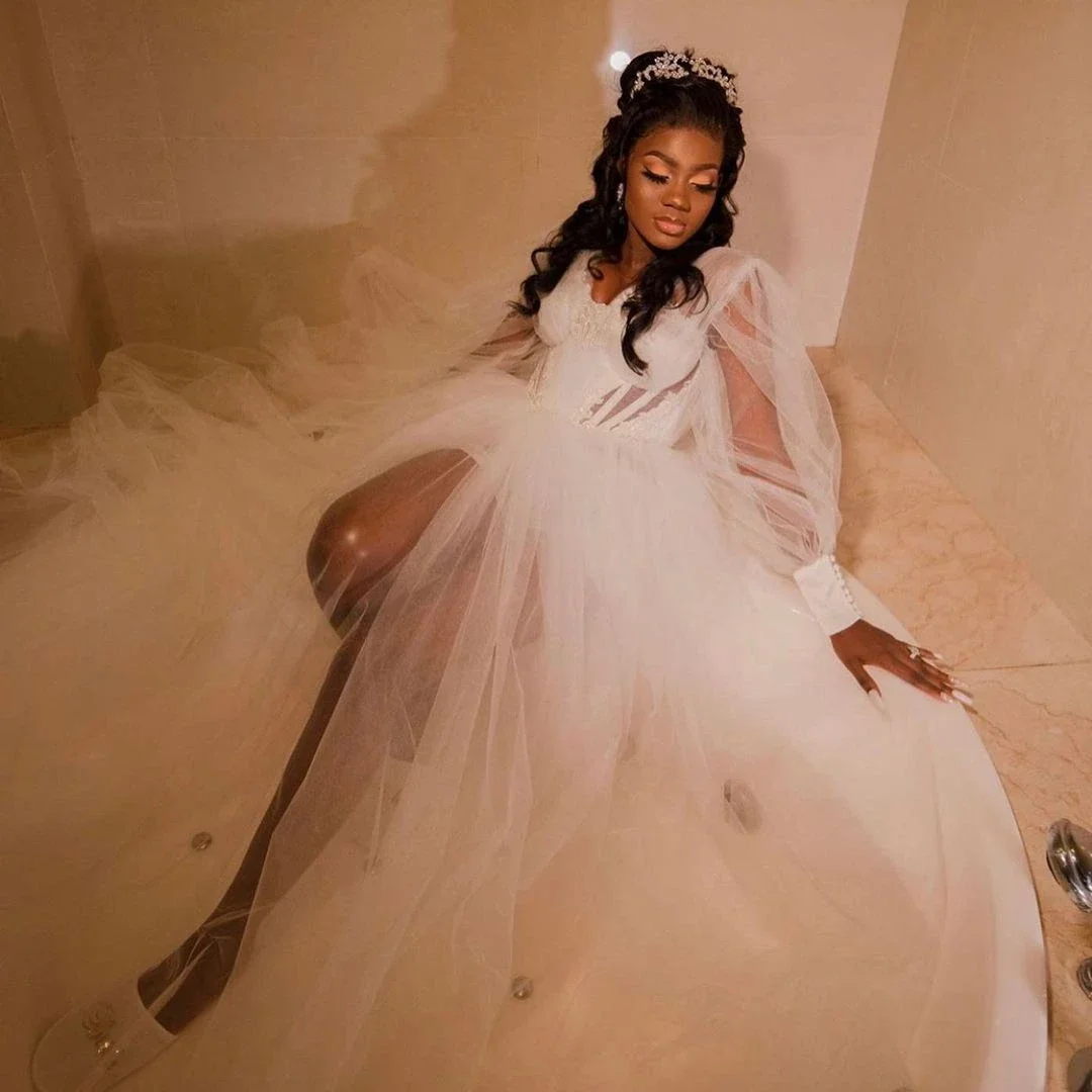 Suknia ślubna w kształcie litery A z dekoltem w serek, tiulowa, z długimi rękawami typu lampion, prześwitująca, z rozcięciem, idealna na przyjęcie weselne.