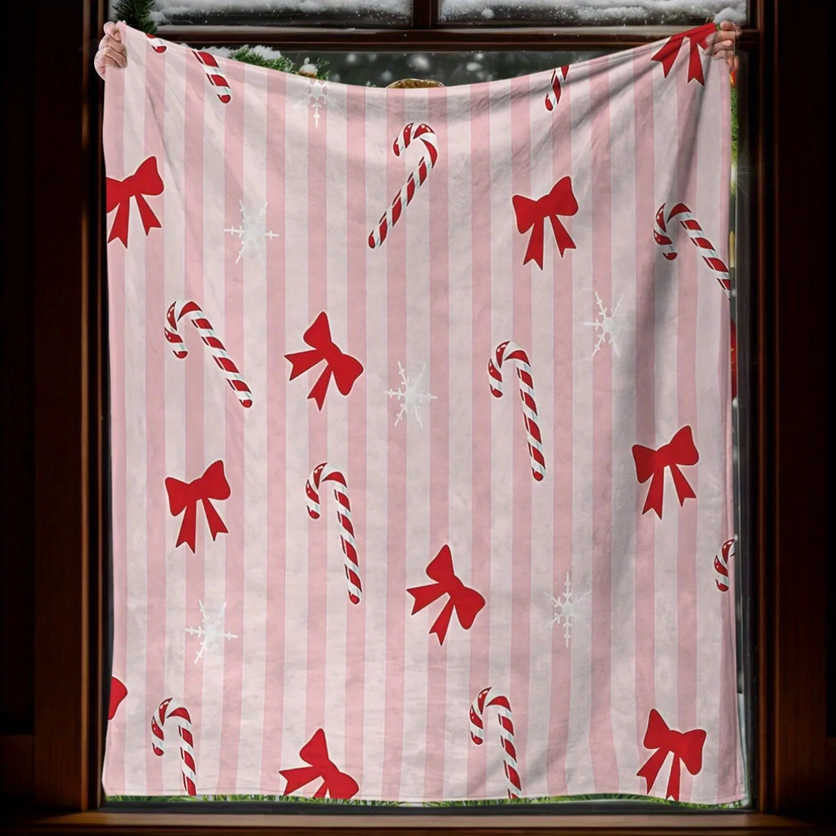 Una pieza de una acogedora manta navideña de franela con diseño de bastón de caramelo y lazo, perfecta para camas o sofás
