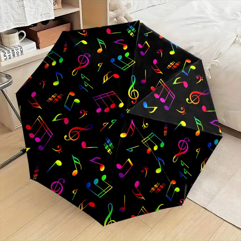 Klappbarer Regenschirm mit buntem Musiknotenmuster, schwarzer Hintergrund. Kreativer tragbarer Faltregenschirm für Weihnachten und andere Feiertage