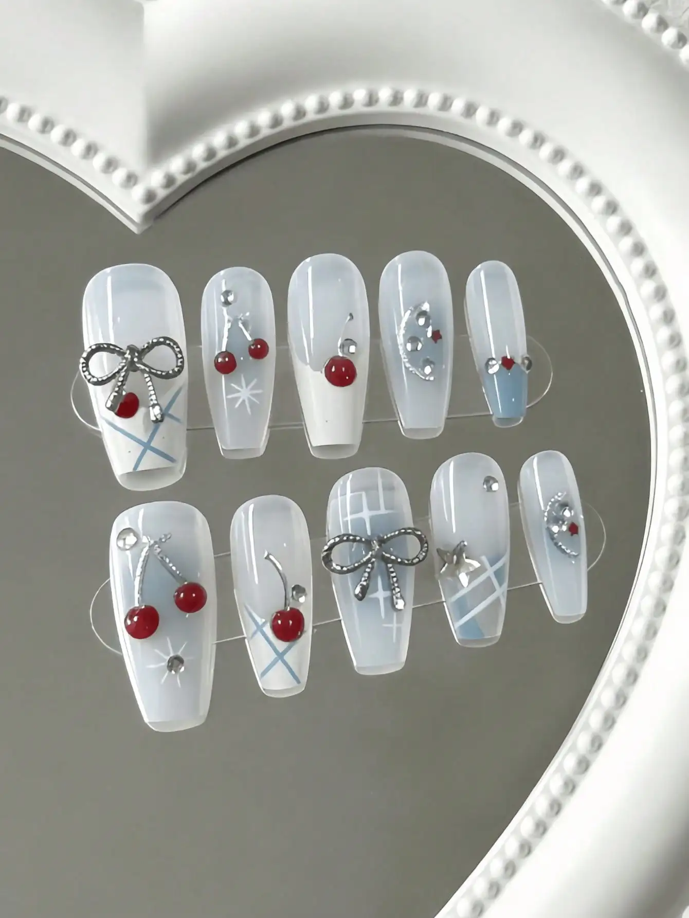 10 Pieces of Medium-Length Ice Blue Cherry Silver Knot Press-On Nails, Featuring a Clear and Sweet Cool Style, with 3D Cherry, Bow, and Metal Star Decorations, Using a Nude Color Gradient and 3D Decoration Techniques, Suitable for Young Girls and Young Women, Perfect for Daily Commuting, Sweet Girl Dates, and Outings, Comes with Jelly Glue and Nail File