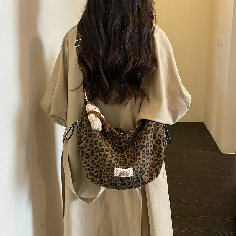 Women's Leopard Print Canvas Hobo Bag Casual Crescent Crossbody Bag with Wide Strap and Bear Pendant for Daily Use