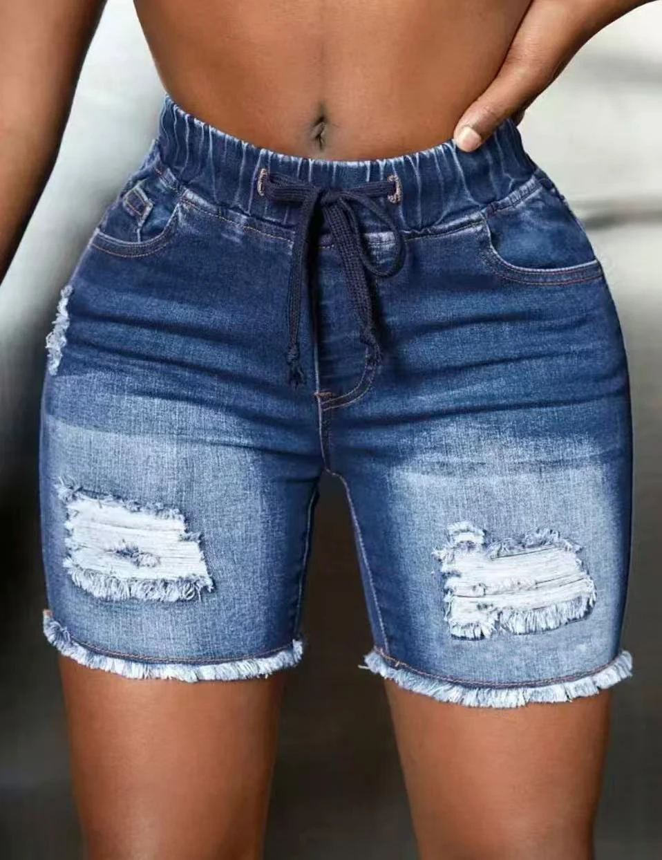 

High-waisted distressed denim shorts with ripped holes and frayed hems, featuring an elastic waistband with drawstring.