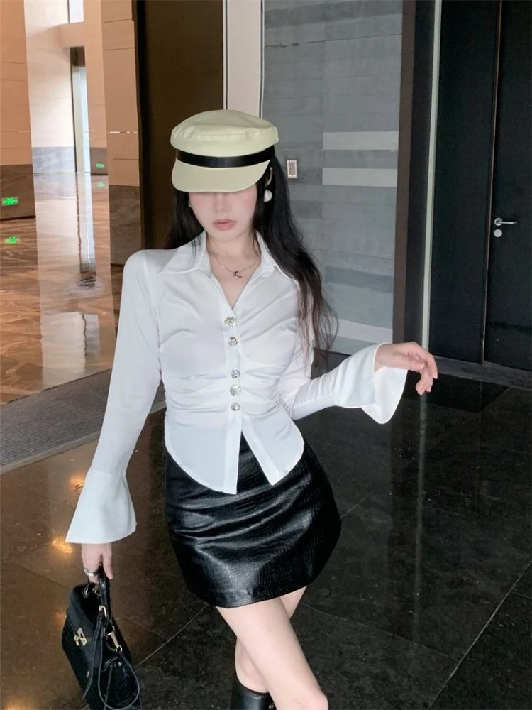 Elegancka damska bluzka z nieregularnym podkreśleniem talii, długim rękawem, z miękkiego, połyskującego materiału, jesienna moda, biała, casualowa, szykowna góra. ​