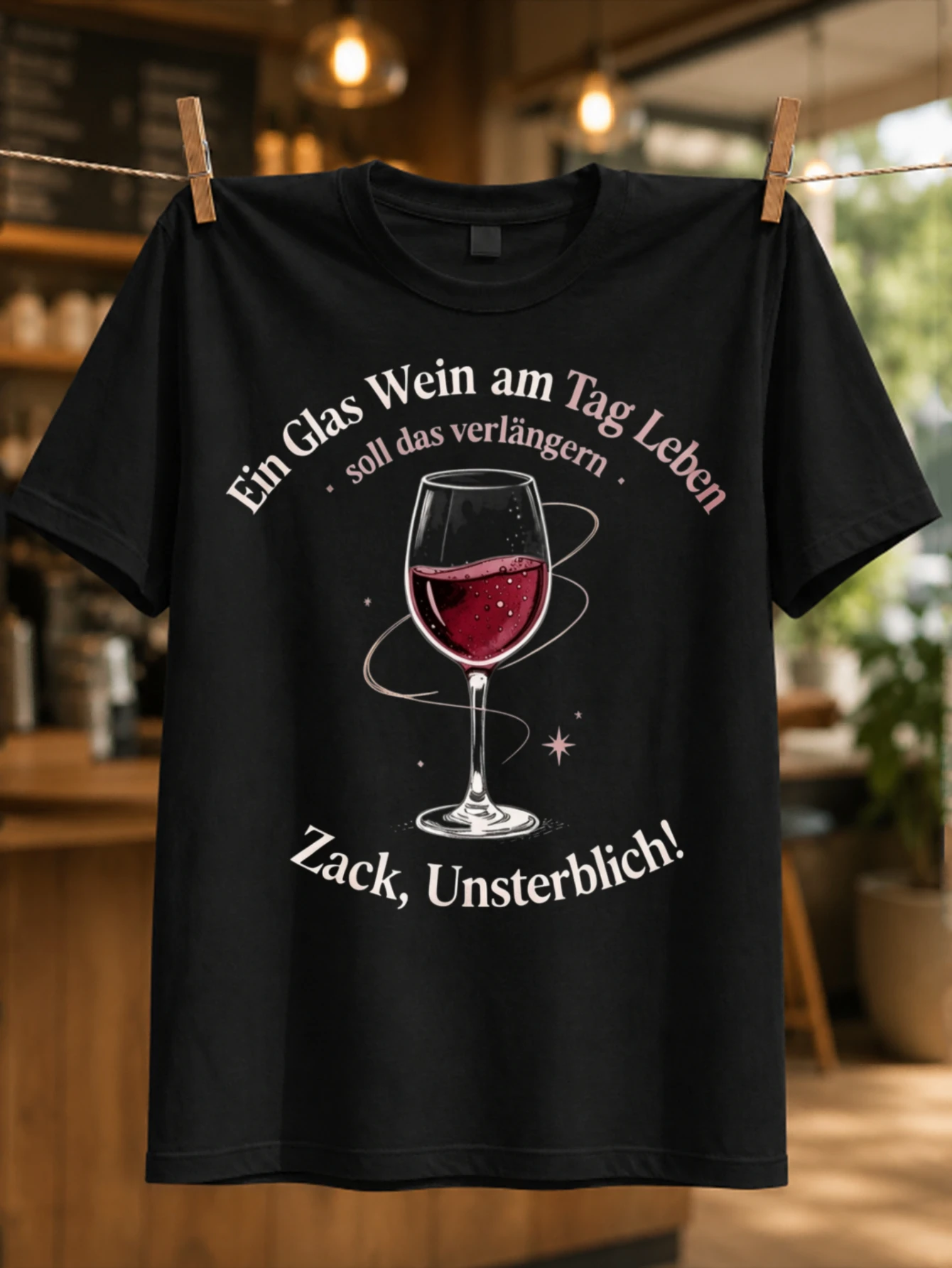 Футболка унисекс с принтом «Ein Glas Wein Am Tag Zack Unsterblich»: сверкающий бокал для красного вина и яркие розовые надписи.