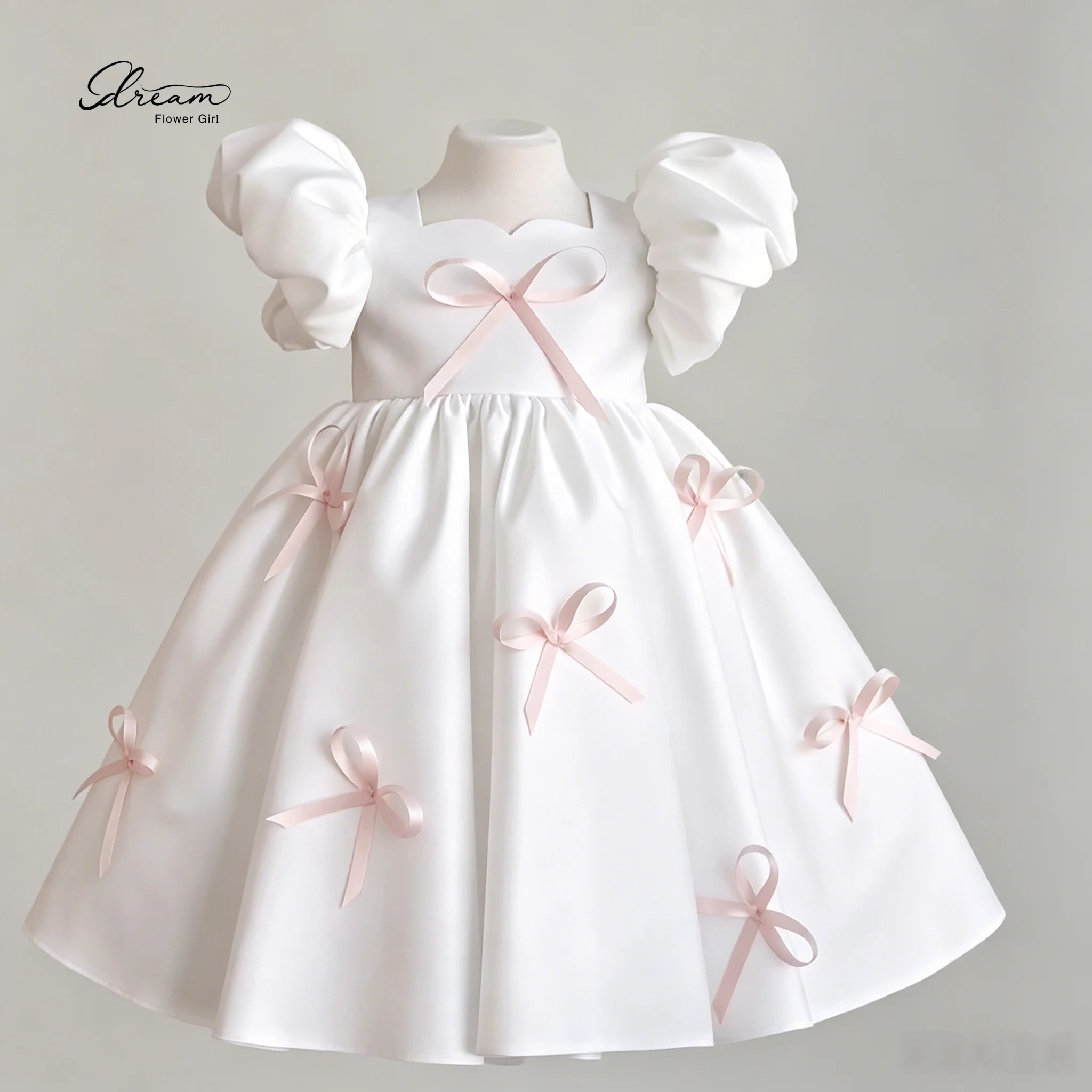 

Exquisite Floor-Length White Formal Gown for Children Featuring Puff Sleeves a Voluminous Skirt and Pink Bow Accents