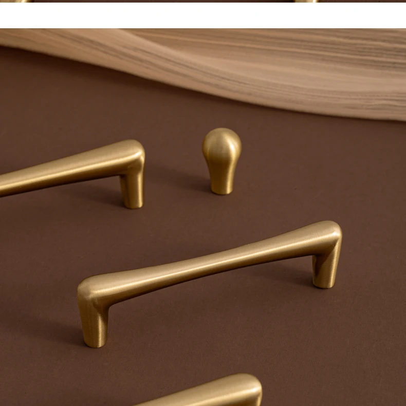 Slim brass pulls and teardrop knob arranged together