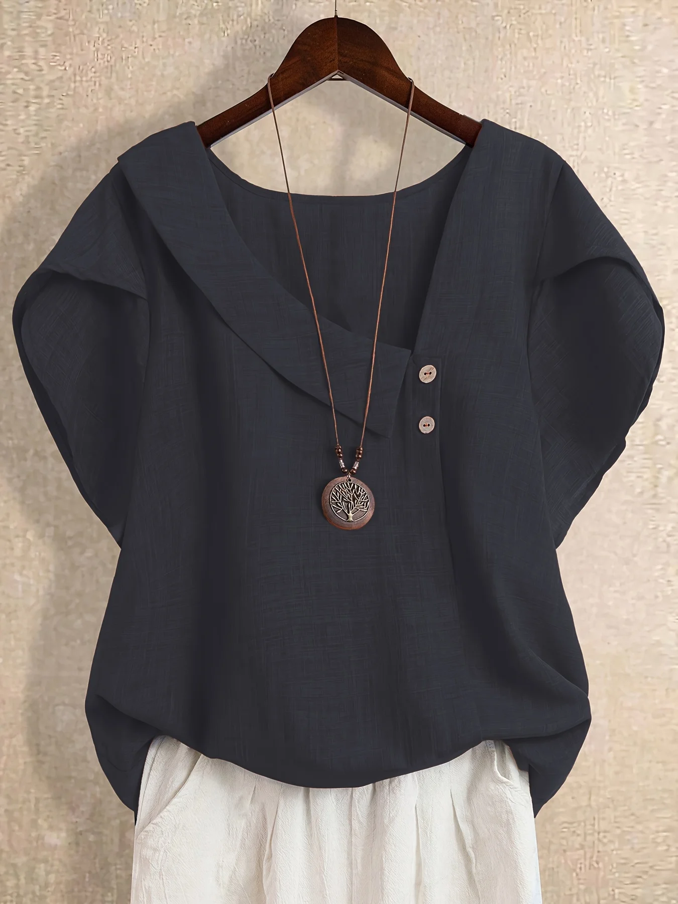 Plus-size women's asymmetrical solid color T-shirt with unique button detail, featuring a comfortable loose fit, suitable for ca