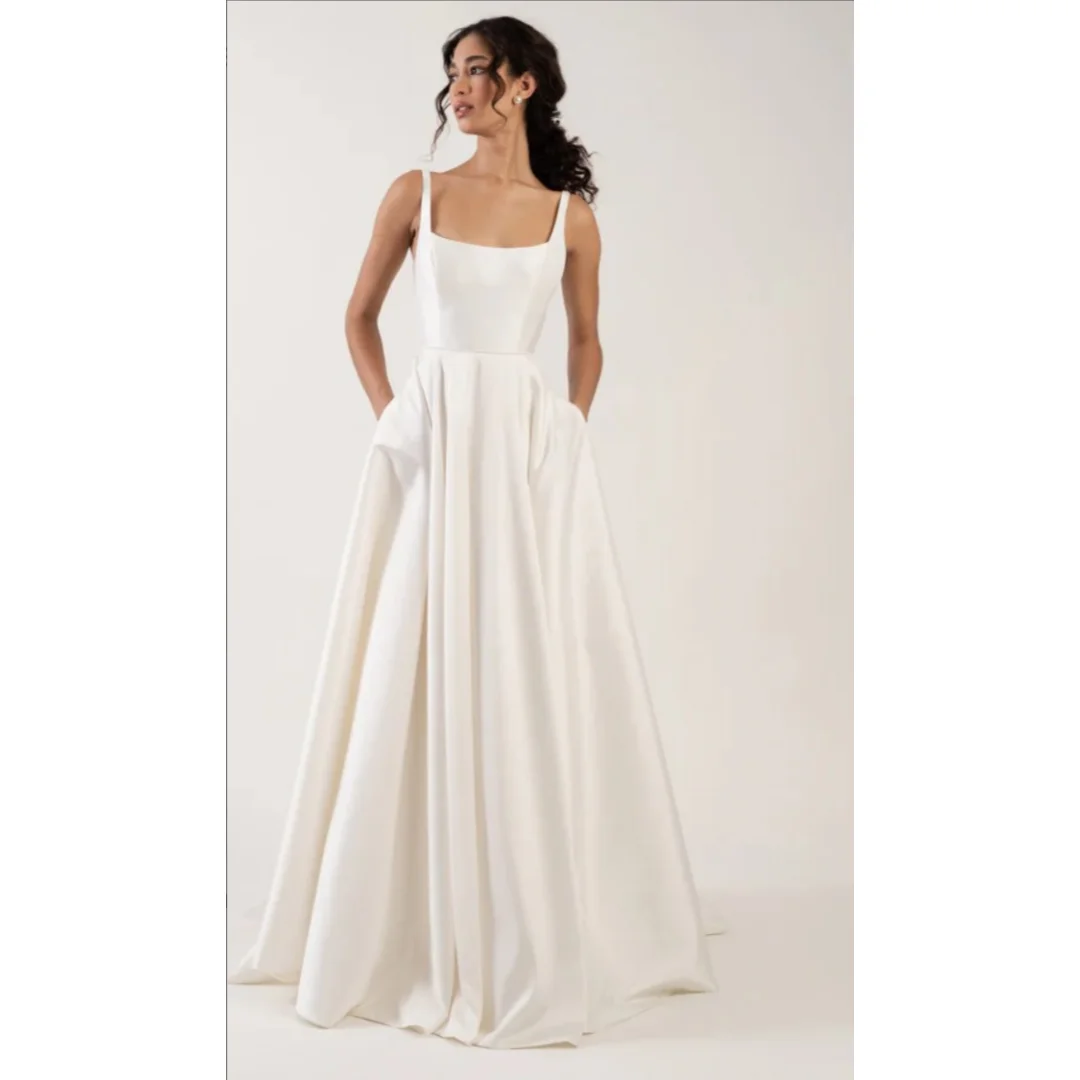 Modern square-neck satin wedding dress with thick straps, open low back, and flowing A-line train. Minimalist chic bridal gown